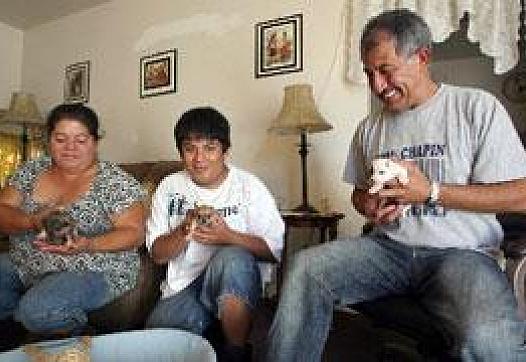 Calixto Orantes, right, his son Julio, 17, center, and wife Edel, left, play with their new puppies at their home.
