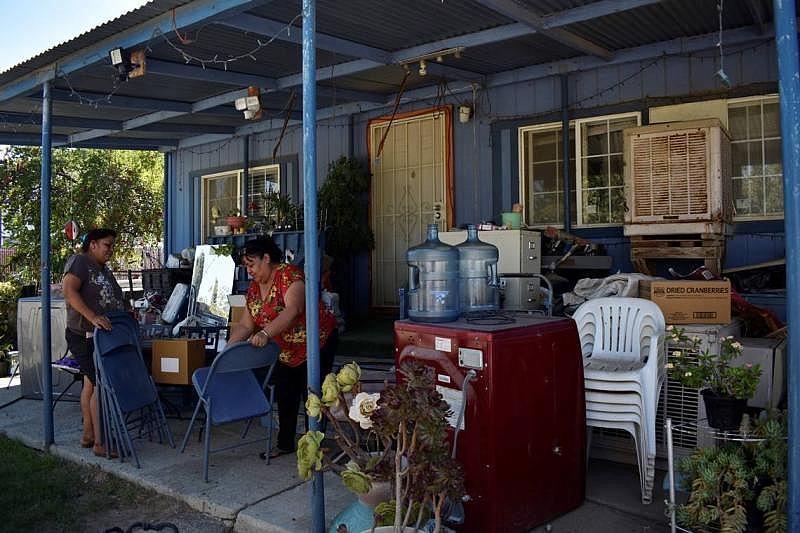 Julia Mendoza, a la izquierda, y Blanca Gómez, a la derecha, limpian el polvo de las sillas plegables en la casa de Gómez el 19 de agosto de 2022. Cuando no pueden encontrar alivio del calor dentro de la casa de Gómez o en su porche delantero, las dos amigas se sientan bajo un árbol en un estacionamiento abandonado. ldiaz@fresnobee.com LAURA S. DIAZ