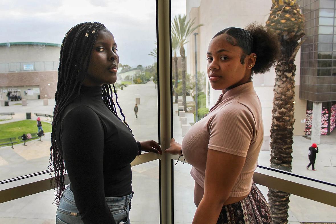 Chrishana Bunting, 16, and Lizette Pierce, 16, pose for a photo inside the Lincoln High School library in San Diego on Feb. 13, 2023. Both friends have experienced sexual comments about their bodies, treated like adults throughout their childhood, and received inappropriate comments about their skin tone. All examples of adultification bias and anti-Blackness. (Anissa Durham/ Word In Black)