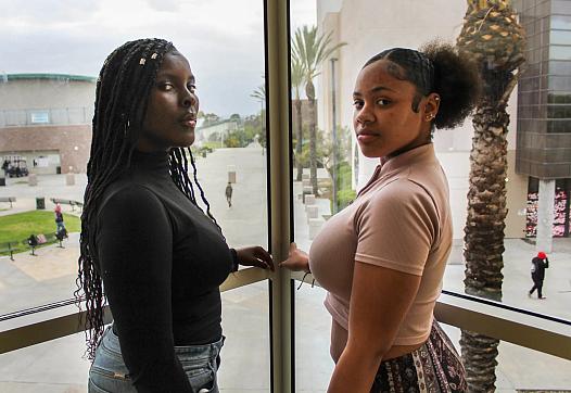 Chrishana Bunting, 16, and Lizette Pierce, 16, pose for a photo inside the Lincoln High School library in San Diego on Feb. 13, 2023. Both friends have experienced sexual comments about their bodies, treated like adults throughout their childhood, and received inappropriate comments about their skin tone. All examples of adultification bias and anti-Blackness. (Anissa Durham/ Word In Black)