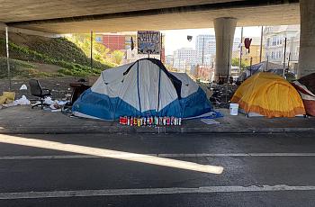 Candles create a vigil outside the tent of an unhoused community member who was shot in West Oakland