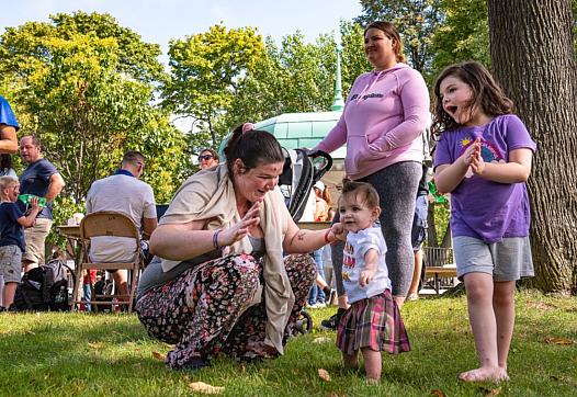 Kirsten Gaddas holds her daughter Oakley Shuman's hand as her other daughter, Sophia Shuman, right, dances to the music