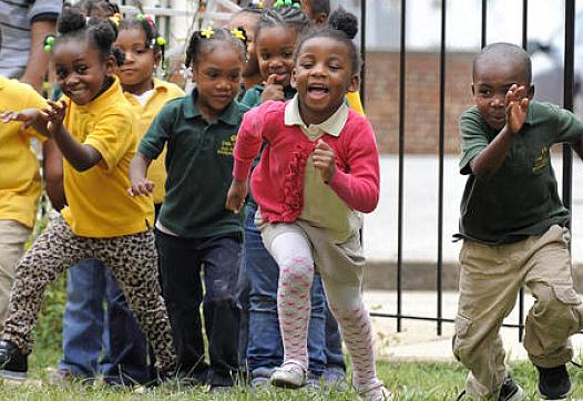 Students at Little Flowers Child Development Center laugh and play during a morning on the playground. Some of the children who attend the Baltimore school are exposed to violence in their neighborhood - an exposure scientists increasingly realize can cause health impacts. (Lloyd Fox, Baltimore Sun)