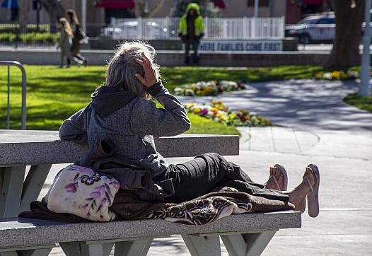 A homeless woman rests on a bench at Todos Santos Plaza in Concord, Calif., on Feb. 15, 2022.