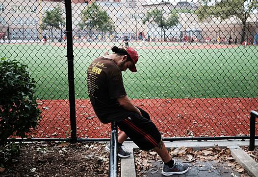 A young man rests after using drugs next to a park.