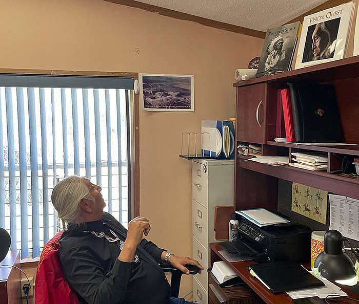 Hollow Horn Bear looks up at a historic photo of the former Saint Francis Indian Mission school grounds at his office on the present day Saint Francis school grounds. The community is in discussion to change the current school name, he said. (Photo/Jenna Kunze)