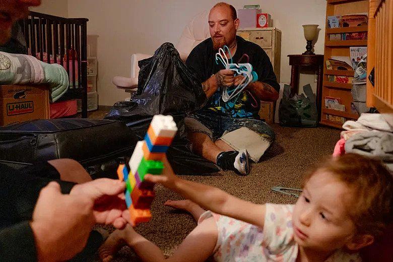 Justin Cortes packs hangers while his friend, Nathan Cook, hangs out with Cortes' daughter, Bethany Cortes, 2. The family is still looking for child care for her near their new place. YEHYUN KIM / CTMIRROR.ORG