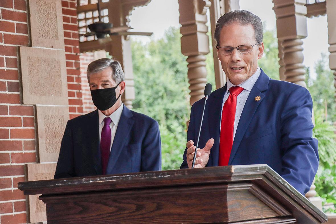 Sen. Steve Jarvis, R-Davidson, speaks at the lectern while Gov. Roy Cooper stands behind him at a bill signing, Thursday afterno