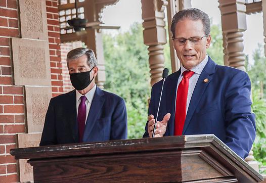 Sen. Steve Jarvis, R-Davidson, speaks at the lectern while Gov. Roy Cooper stands behind him at a bill signing, Thursday afterno