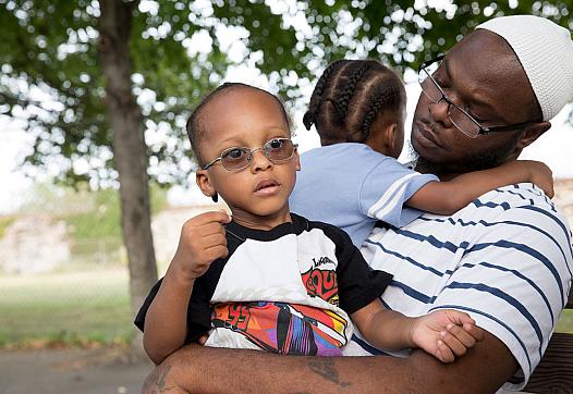 (Left to Right) Jihad and Murad sit with their dad, Andrew Irby, in the park. Irby worries about the future of his twin sons.