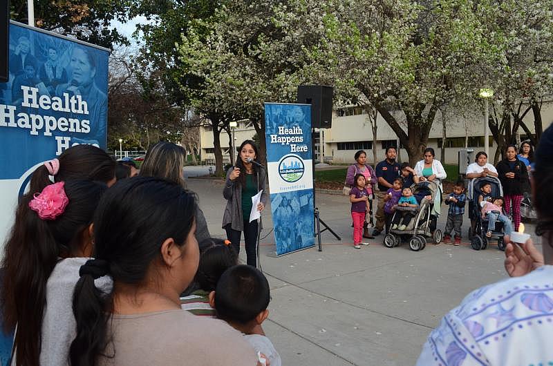 A woman lights a candle to start a vigil for support of a Fresno County program to provide medical services to undocumented immigrants. (Photo by Juan Santiago/Radio Bilingue)