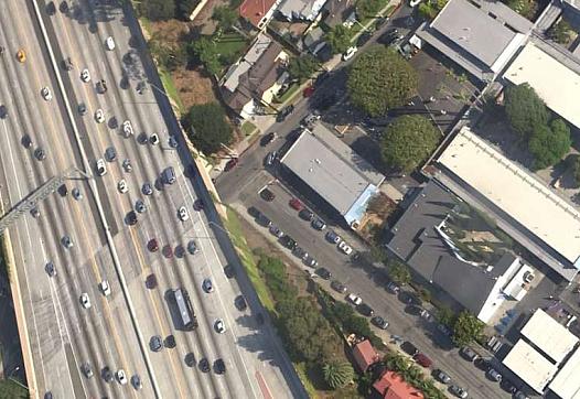 Students line up outside El Marino Language School as vehicles zoom by on Interstate 405 in Culver City, California.