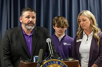 Man delivering speech with his son and wife.