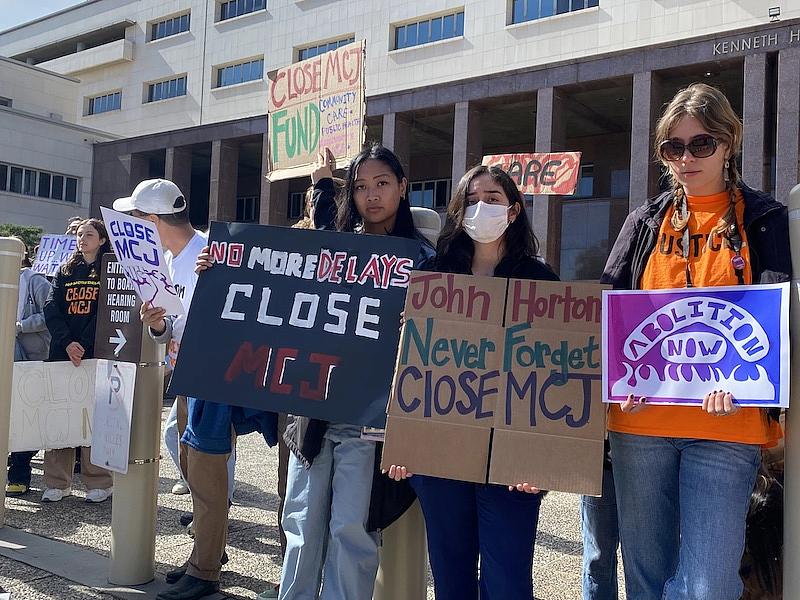 Protesters holding boards for closure of MCJ