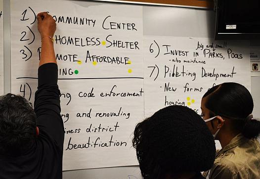 Stickers representing money from federal pandemic relief funding are placed alongside community needs by participants in a commu