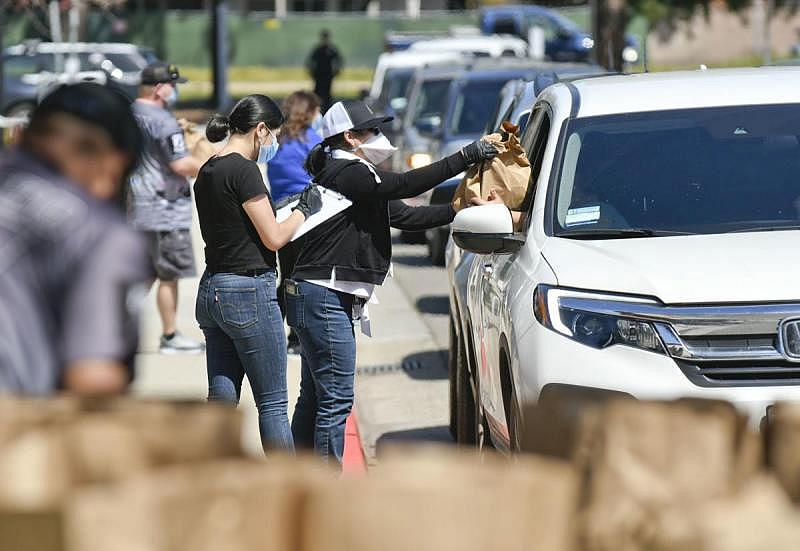 As cars line up on the Santa Maria campus, Hancock College staff and volunteers hand off hundreds of food bags during a drive-through distribution on March 31, 2020.  Len Wood, Staff file