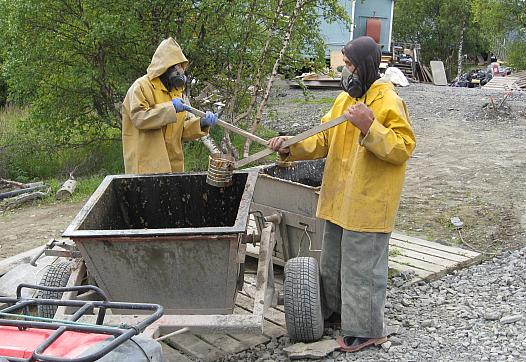 A 2011 photo shows residents of Pitkas Point, Alaska wearing breathing apparatus to transfer human waste to a collection bucket,