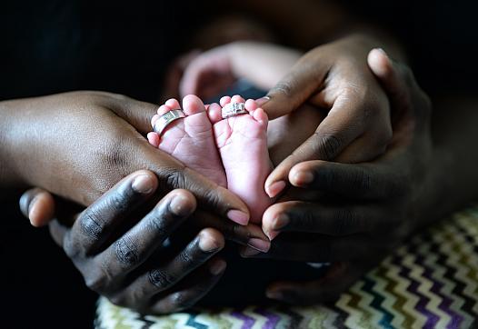Closeup image of a baby's feet being held by their parents