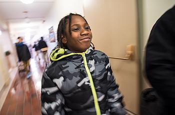 An image of a boy smiling in a corridor while walking.