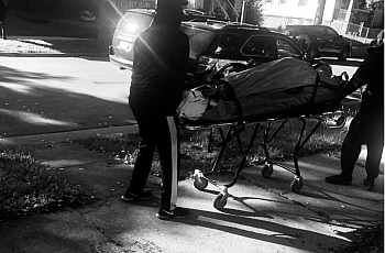 Black and white image of two people with Corpse on a stretcher.